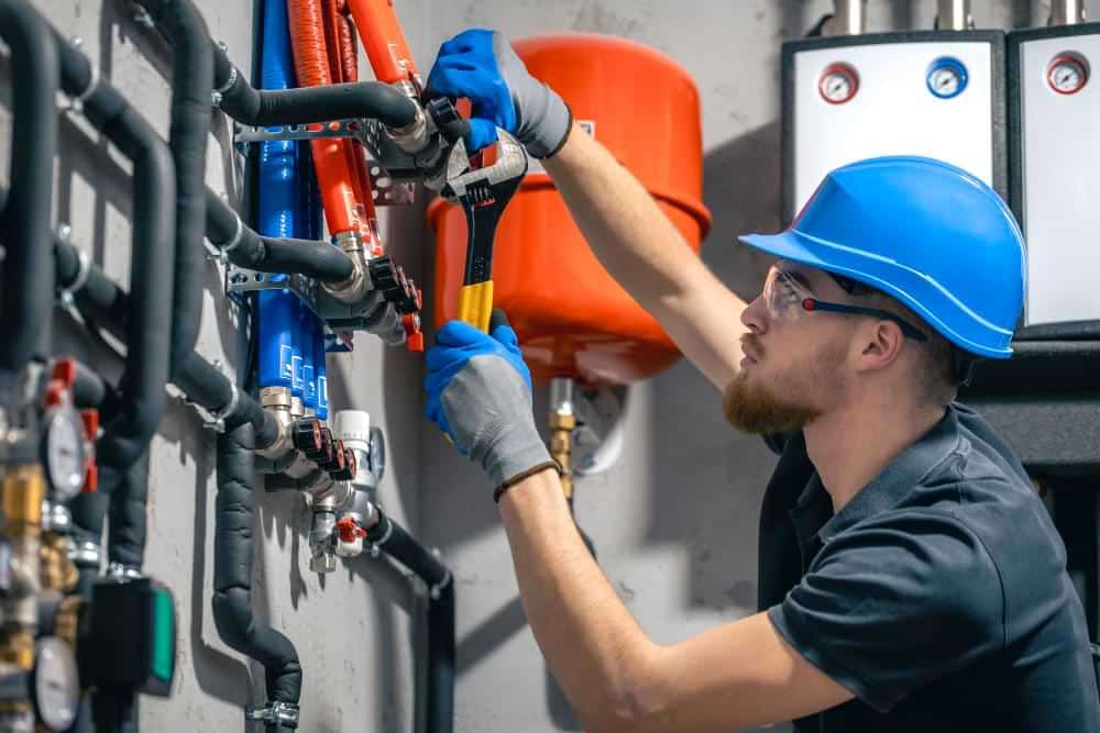 A plumber uses a wrench on complex pipes.