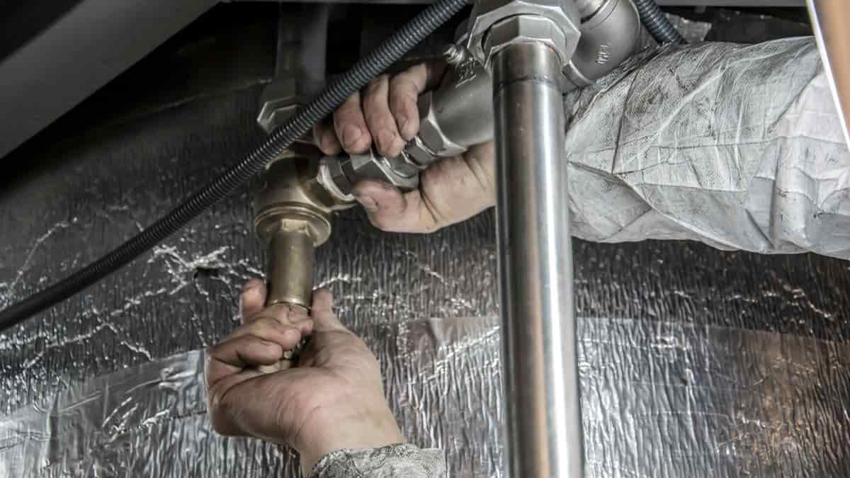Plumber's hands installing steel pipes indoors representing skilled drain maintenance