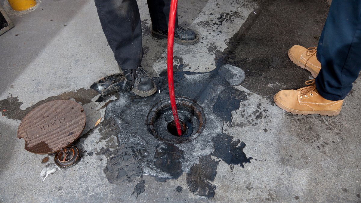 red hydro jetting hose is fed into an open drain