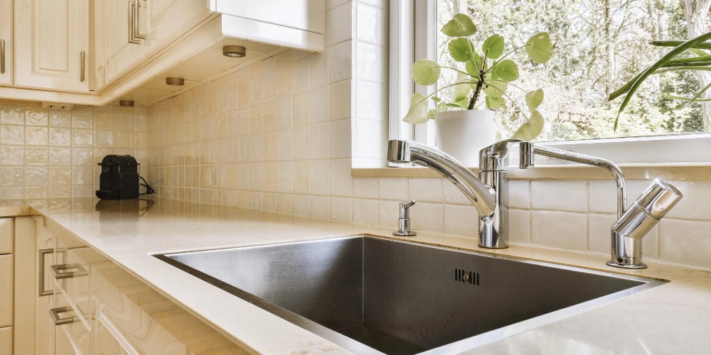 Kitchen sink with countertop and window view.
