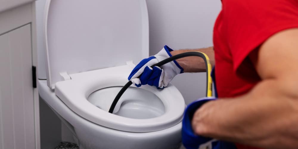Plumber inserting a flexible toilet auger