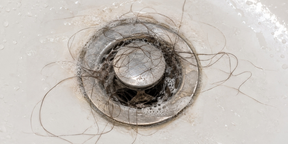 bathtub drain covered in hair and soap residue