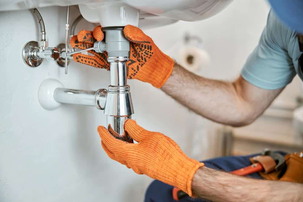 male plumber hands fixing metal sink pipe
