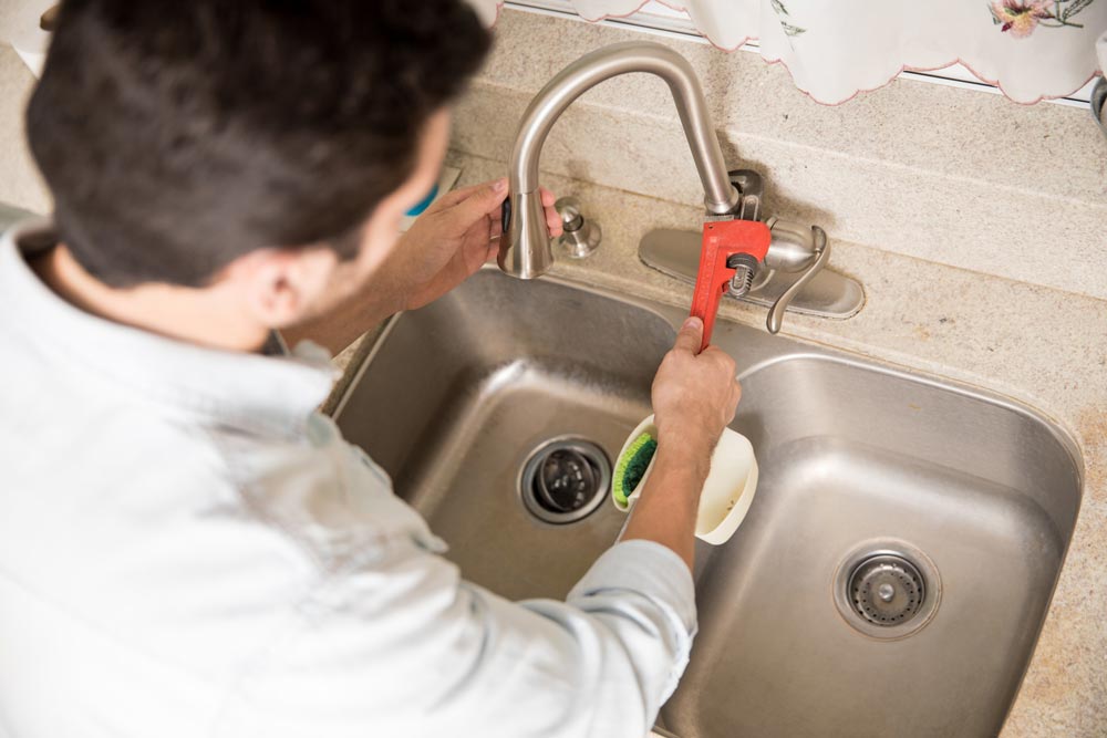 male plumber using wrench tighten water faucet